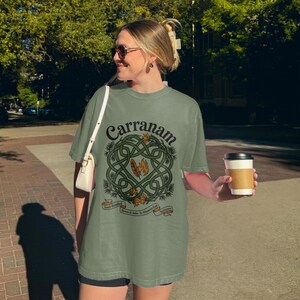 Woman wearing a green t-shirt with a Celtic knot design and "Carranam" text.