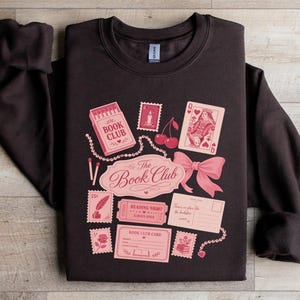 Dark sweatshirt with "The Book Club" design featuring playing cards and mail.