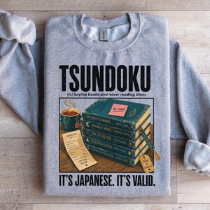 Gray sweatshirt with "Tsundoku" definition and stack of books.