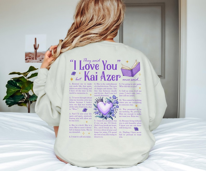 a woman sitting on top of a bed wearing a sweatshirt