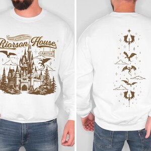 a man wearing a white sweatshirt with a picture of a castle on it