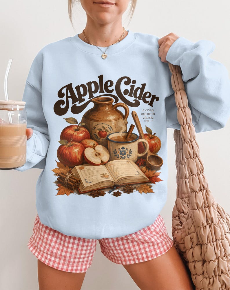 "Apple Cider a crisp autumn classic" graphic on light blue sweatshirt.