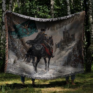 Puede incluir: Un tapiz tejido que representa a un caballero a caballo en un paisaje nevado con un castillo al fondo. El tapiz tiene un borde con flecos y una paleta de colores negro, gris y verde azulado.
