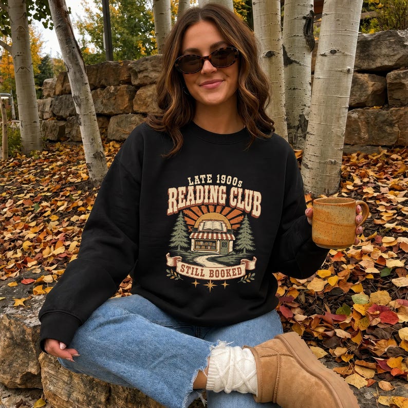 Black sweatshirt with "Late 1900s Reading Club Still Booked" graphic.