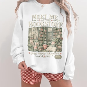 White sweatshirt with "Meet Me at the Bookstore" text and cozy library graphic.