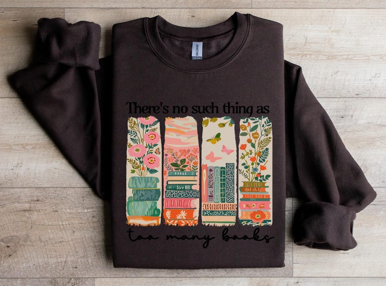Dark brown sweatshirt with stacked books and floral design, reading "There's no such thing as too many books".