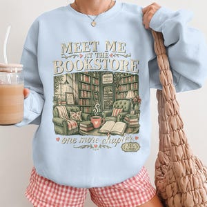 Light blue sweatshirt with "Meet Me At The Bookstore" and bookstore illustration.