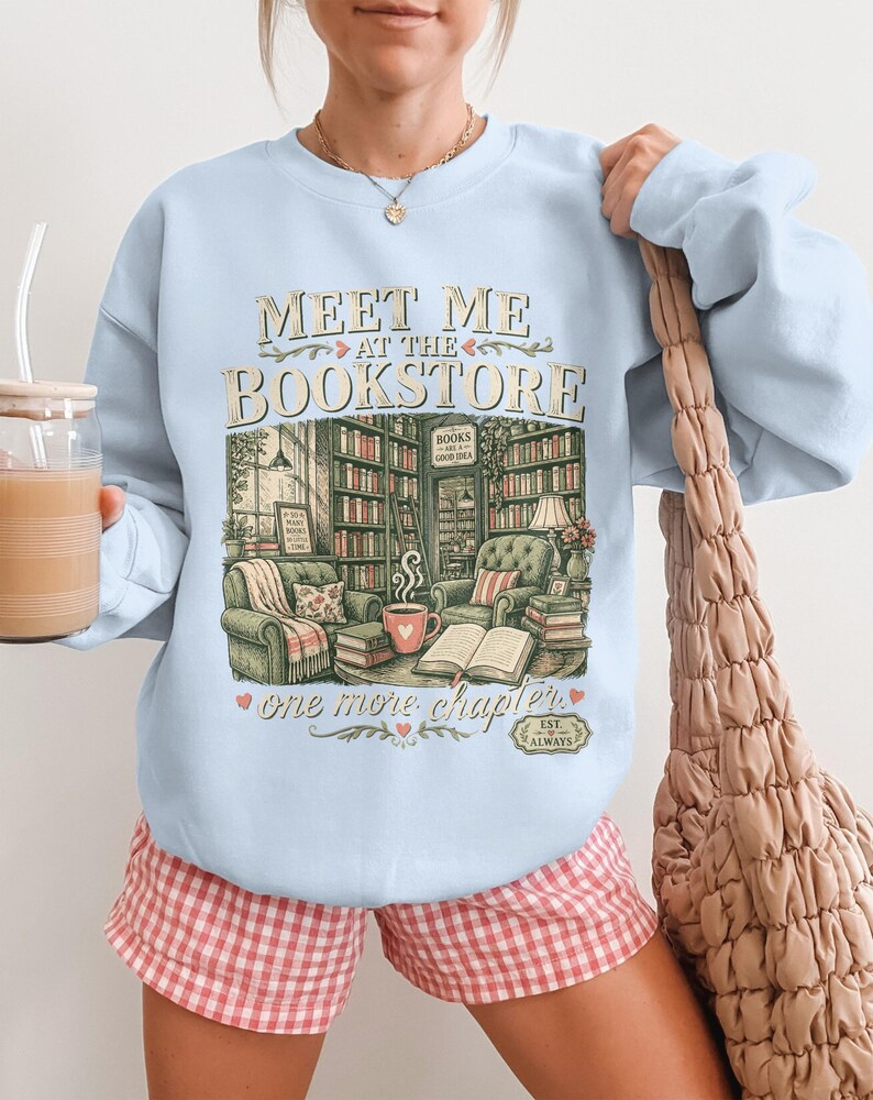 Light blue sweatshirt with "Meet Me At The Bookstore" and bookstore illustration.