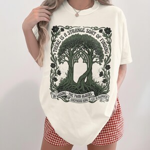 Cream t-shirt with an illustration of two intertwined trees and text.