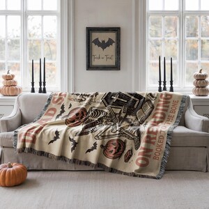 a living room with a couch, a Halloween-themed throw blanket, and a framed sign on the wall.