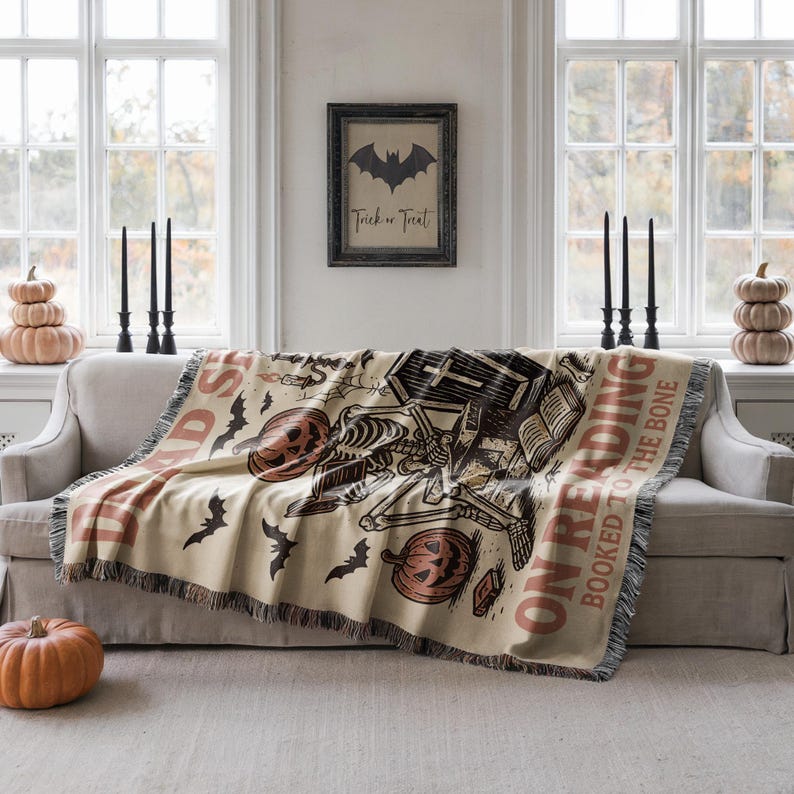 a living room with a couch, a Halloween-themed throw blanket, and a framed sign on the wall.