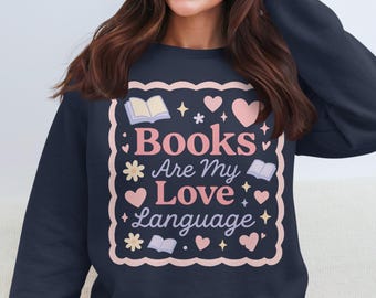 May include: Navy blue sweatshirt with a decorative design. The design features the text "Books Are My Love Language" in pink and white, surrounded by hearts, flowers, and open book illustrations.