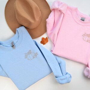 three sweaters and a hat on a white surface