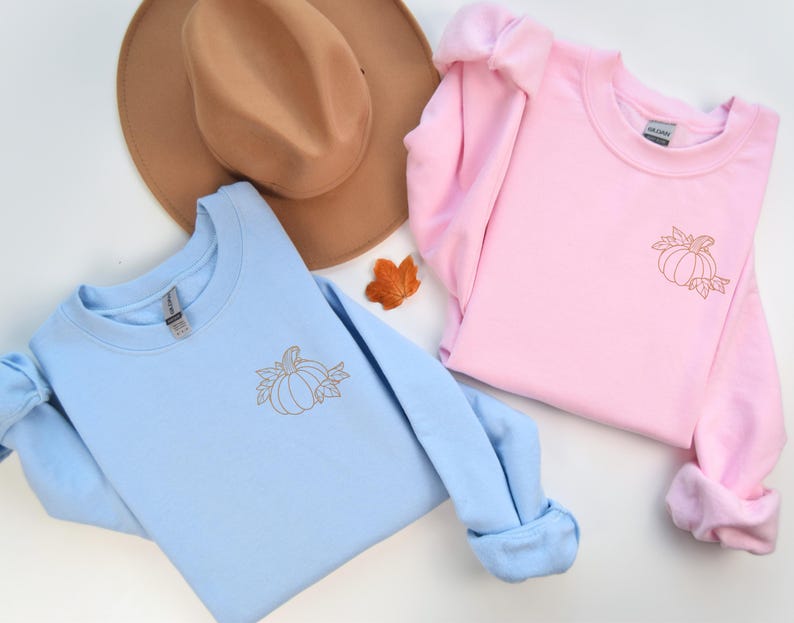 three sweaters and a hat on a white surface