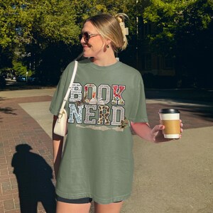 T-shirt with "BOOK NERD" text in floral and vintage letter patterns.