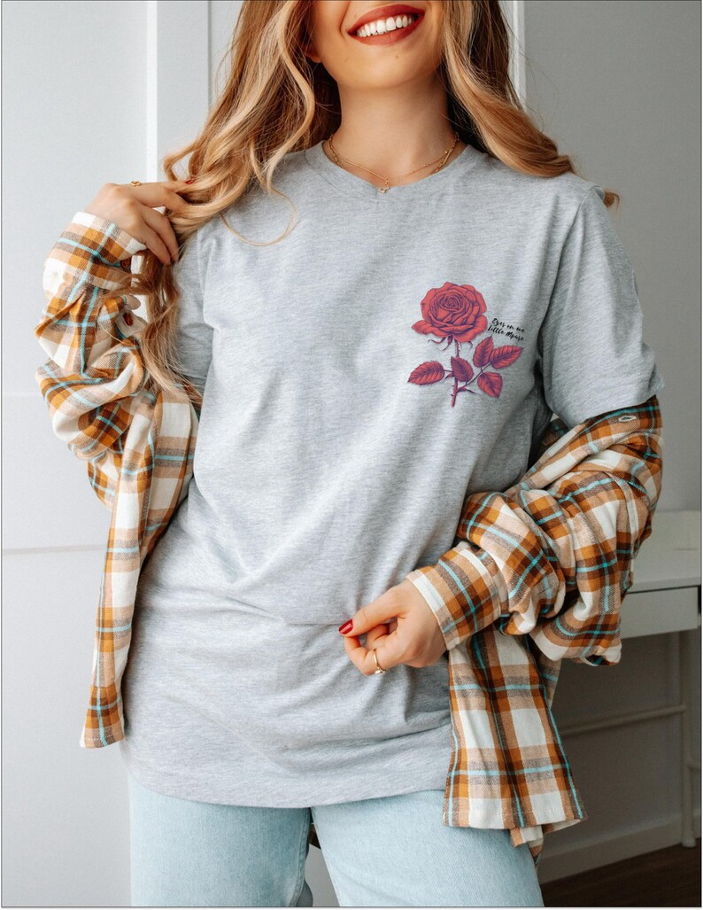 a woman wearing a grey shirt with a rose on it