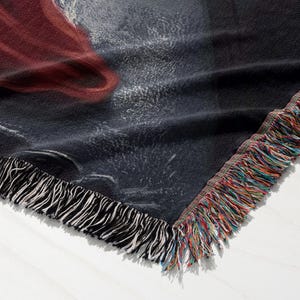 a close-up view of a black and red fabric with a fringed edge, showcasing its texture and pattern.