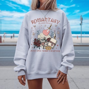 a woman wearing a sweatshirt with a book and heart on it