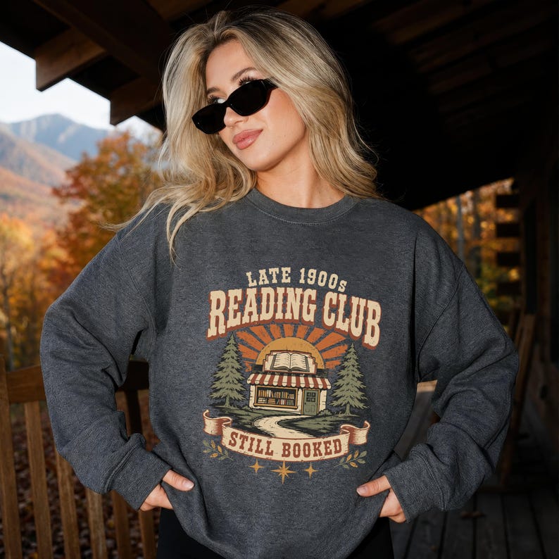 Dark grey sweatshirt with "Late 1900s Reading Club Still Booked" graphic.