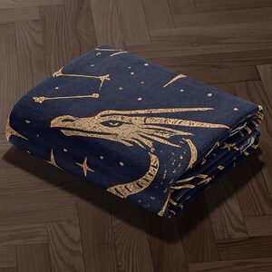 a dark blue blanket with a dragon design, including stars and a star-like pattern, on a wooden floor.