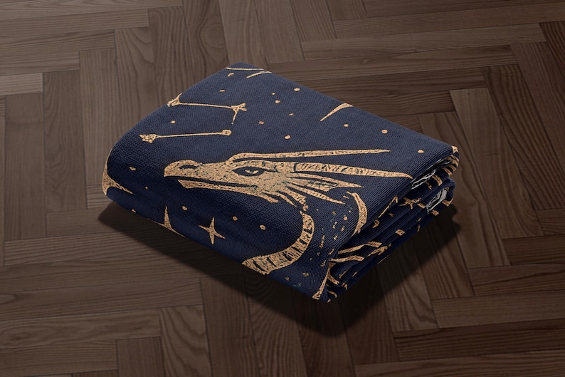 a dark blue blanket with a dragon design, including stars and a star-like pattern, on a wooden floor.