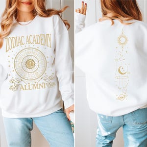 a woman wearing a white sweatshirt with gold lettering