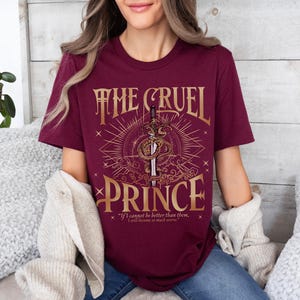 a woman sitting on a bed wearing a t - shirt that says the cruel prince