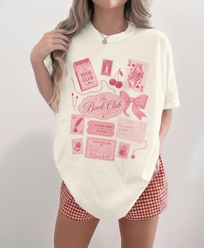 Cream t-shirt with pink "The Book Club" graphic featuring stamps and playing cards.