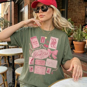 Green t-shirt with pink book club themed graphics and text.