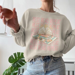 Cream sweatshirt with "Rest, Read, Repeat" and "poolside reader club" text.