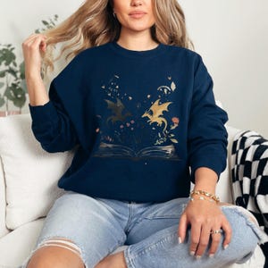 a woman sitting on a couch wearing a blue sweatshirt