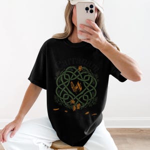 Black t-shirt with green Celtic knot design and orange flames and feathers.