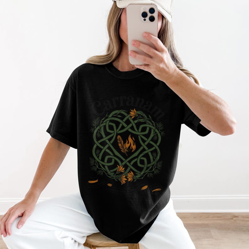 Black t-shirt with green Celtic knot design and orange flames and feathers.