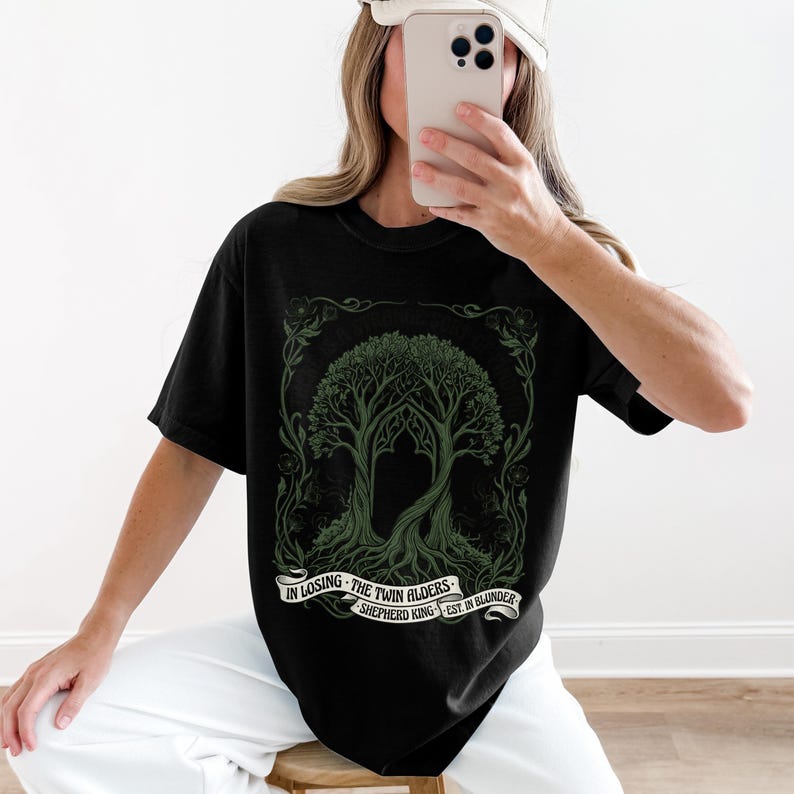 Black t-shirt with twin trees design and text "In Losing The Twin Alders Est. In Blunder Shepherd King".