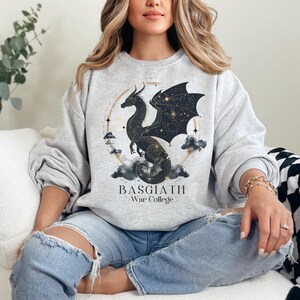 a woman sitting on a couch wearing a sweatshirt with a dragon on it