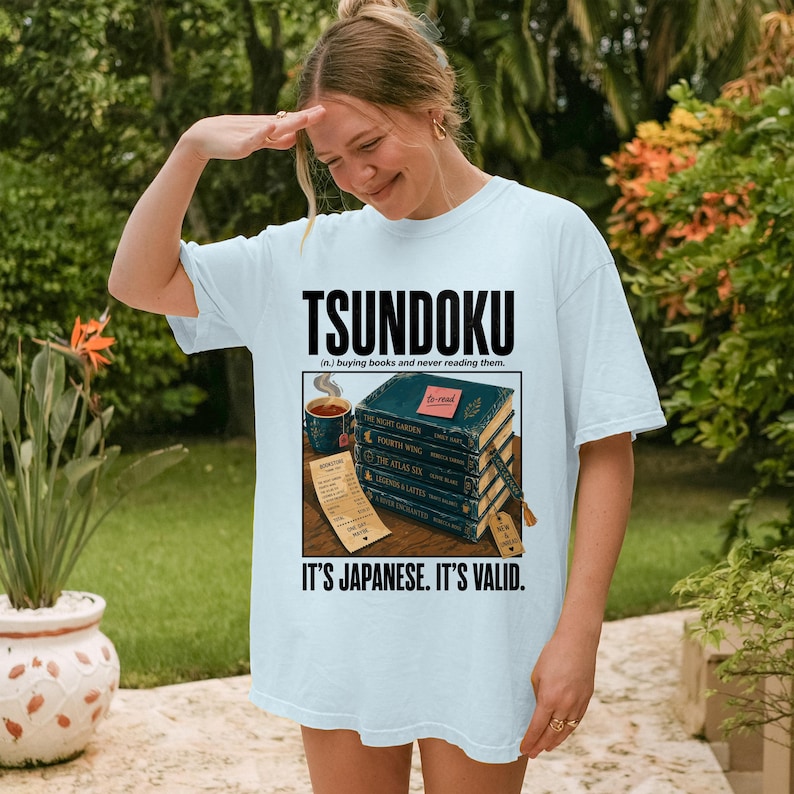T-shirt with "Tsundoku" text and stacked books graphic.