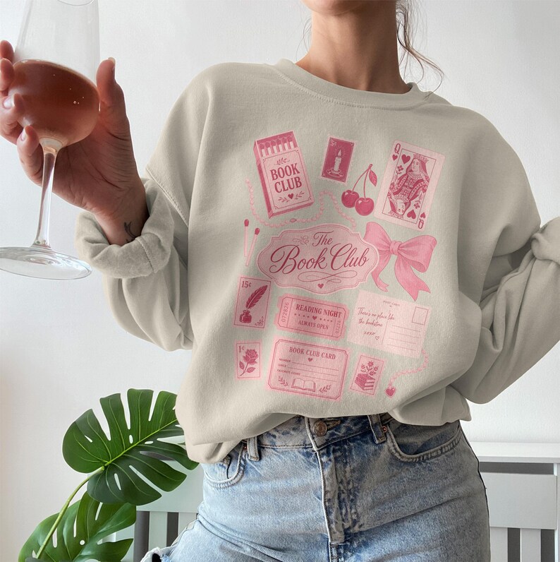Light pink sweatshirt with book club themed graphics and text.