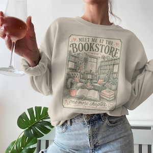 Cream sweatshirt featuring a vintage bookstore illustration and text about reading.