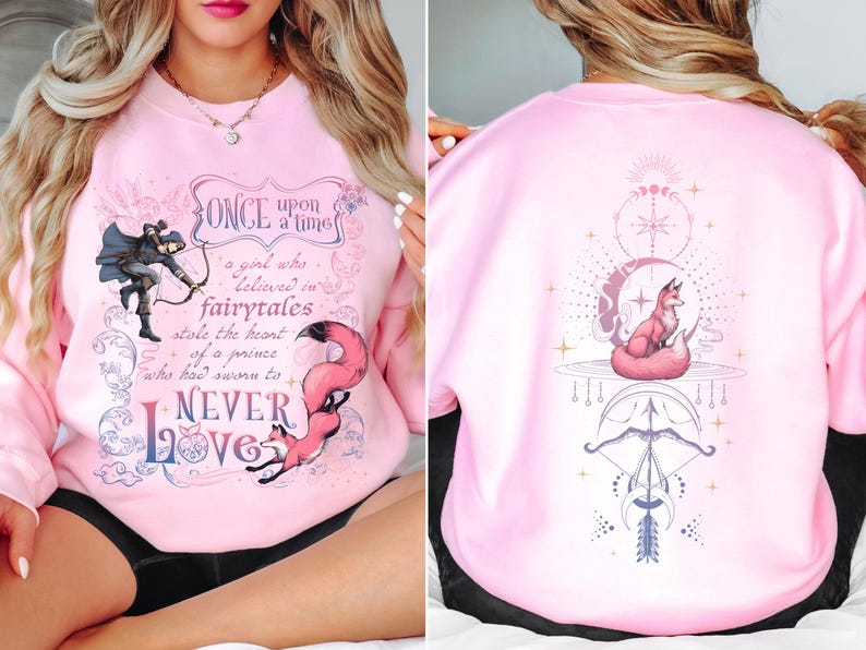 a woman sitting on a bed wearing a pink sweatshirt