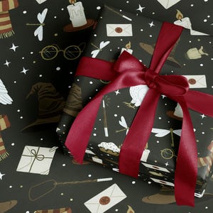 May include: A wrapped gift with black paper featuring white stars and illustrations of a sorting hat, glasses, and candles. A deep red satin ribbon is tied in a bow around the gift. The gift wrap has a magical theme.