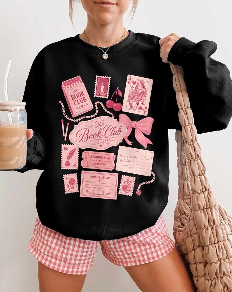 Black sweatshirt with pink book-themed graphics and text reading "The Book Club".