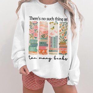 Sweatshirt with stacked books, floral patterns, and the phrase "There's no such thing as too many books."