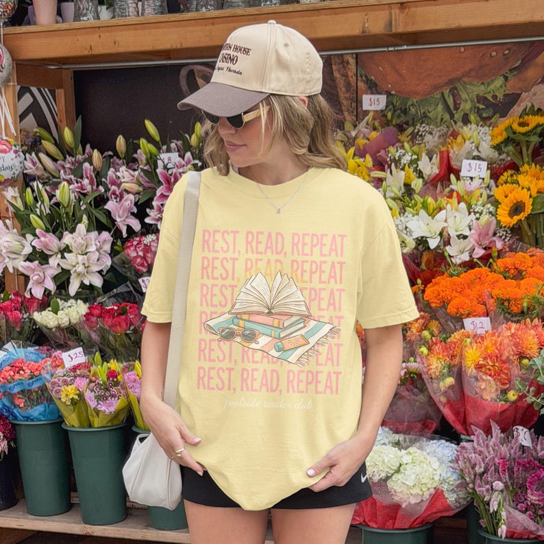 Woman in tan cap wearing t-shirt with "REST, READ, REPEAT" text.