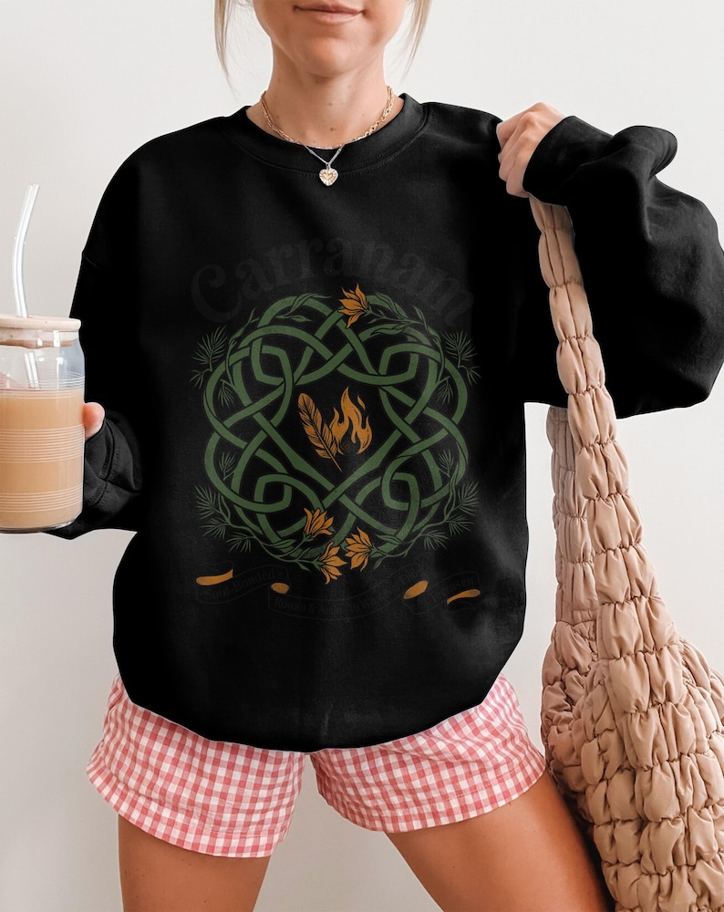 Black crewneck sweatshirt with Celtic knot design and feather emblem.