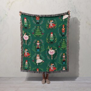 a woman holding up a green christmas blanket