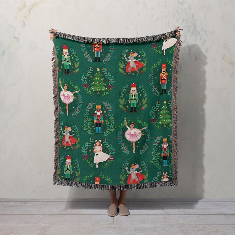 a woman holding up a green christmas blanket