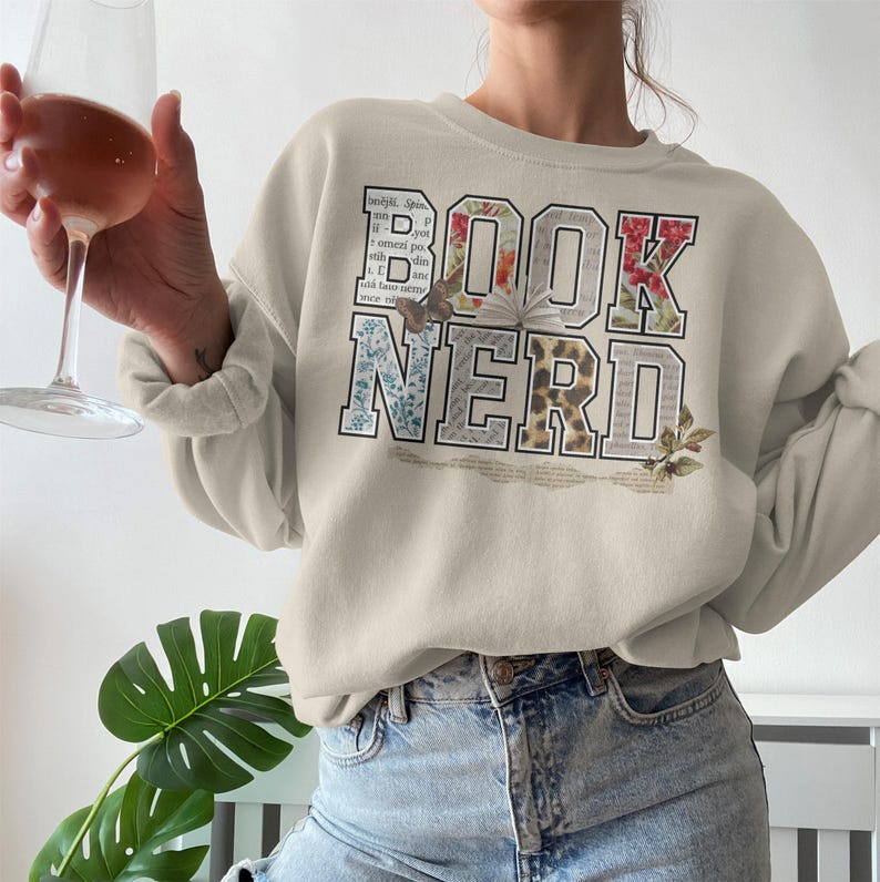 Cream sweatshirt with "BOOK NERD" text in a collage of floral and book page patterns.