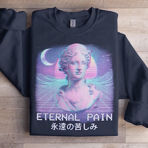 Puede incluir: Sudadera azul marino con un diseño de estilo vaporwave de un busto clásico. El diseño incluye una combinación de colores rosa y azul, una luna creciente y el texto "ETERNAL PAIN" en blanco, con caracteres japoneses debajo.
