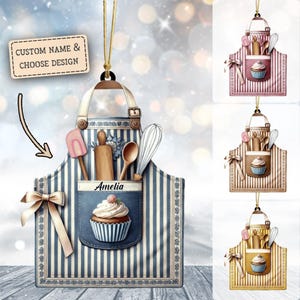 May include: A blue and white striped apron with a pocket featuring a cupcake and the name Amelia. The apron has a variety of kitchen tools in the pocket, including a rolling pin, a spatula, a wooden spoon, and a whisk. The apron is a Christmas ornament.