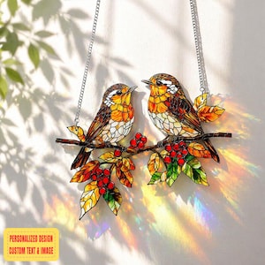 May include: Stained glass window art featuring two birds perched on a branch with red berries and colorful leaves. The birds have brown, orange, and white details. The artwork hangs from a silver chain. Text on the bottom reads: PERSONALIZED DESIGN CUSTOM TEXT & IMAGE.